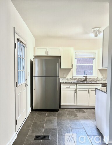 A kitchen with a refrigerator, cabinets, and a window.