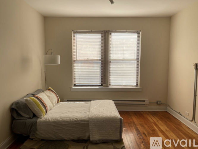 A bedroom with a bed and a window with blinds.