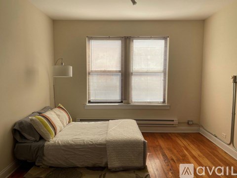 A bedroom with a bed and a window with blinds.