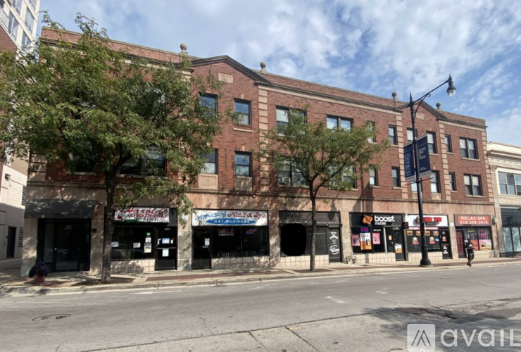 A street view of a brick building with closed shops on the ground floor.