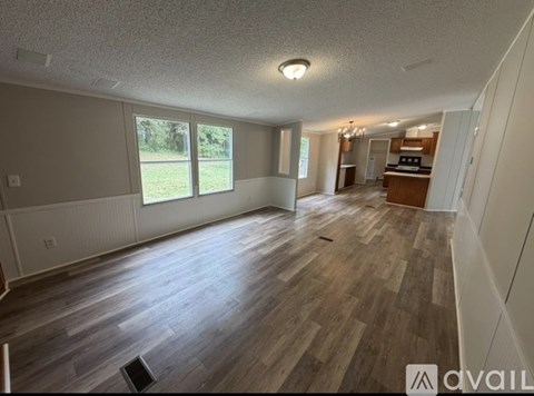 A spacious living room with wood flooring and a large window.