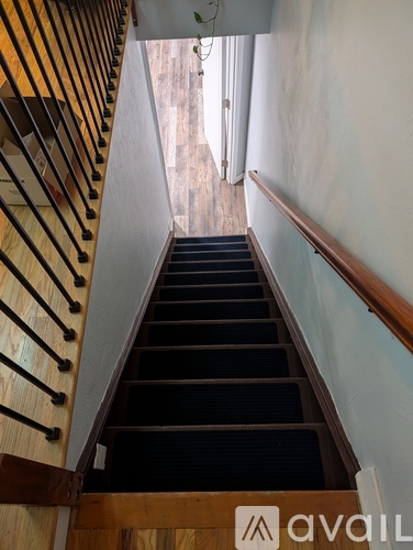 A wooden staircase with a black carpeted runner.
