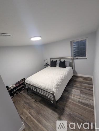 A bedroom with a white bed and wooden flooring.