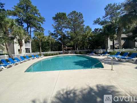 A pool surrounded by trees and chairs.