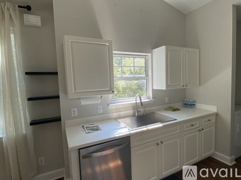 A kitchen with white cabinets and a window.