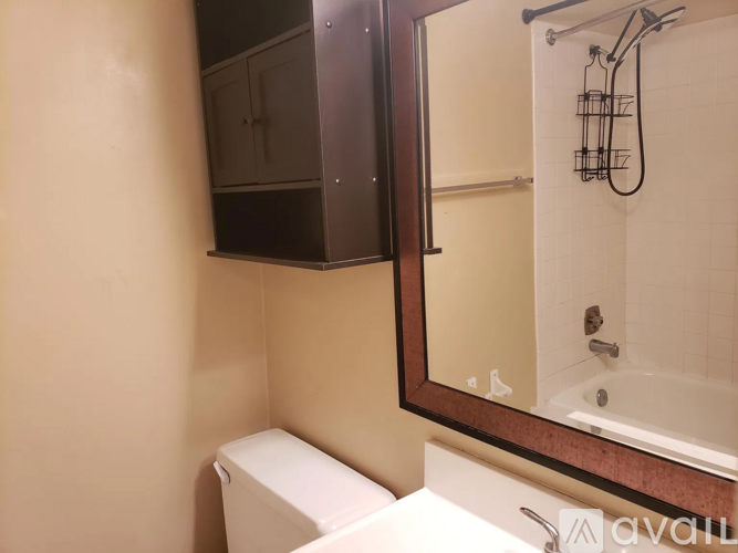 A bathroom with a toilet, a mirror, and a cabinet.