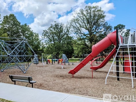 A playground with a red slide and a metal structure.