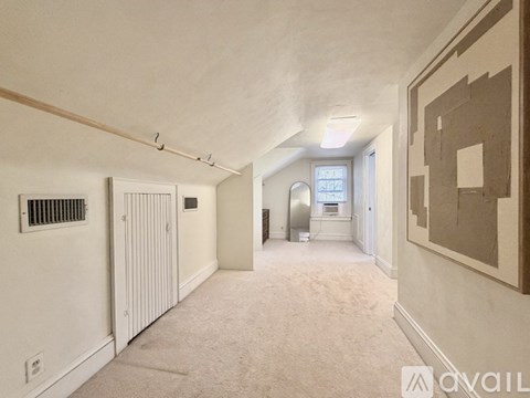 A spacious, empty room with a carpeted floor and a painting on the wall.