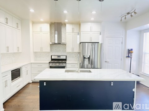 A kitchen with white cabinets and a black island.