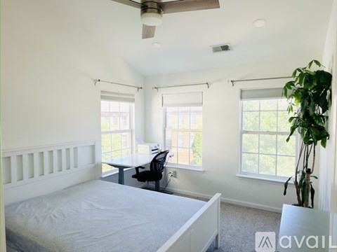 A bedroom with a bed, desk, and window.