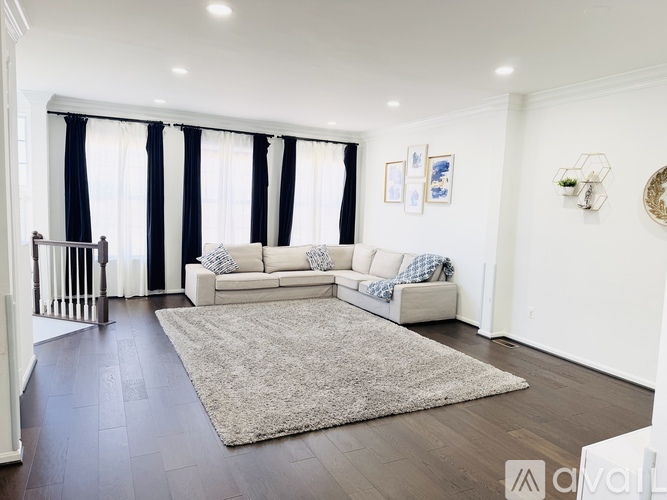 A living room with a white couch and a rug in the middle.