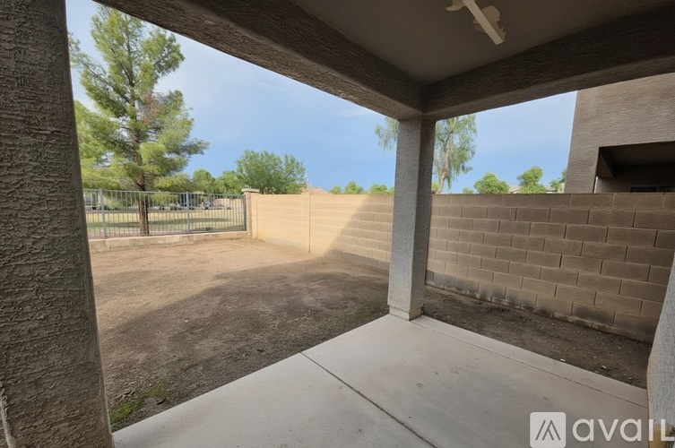 A view from inside a building looking out to a dirt area and a fence.