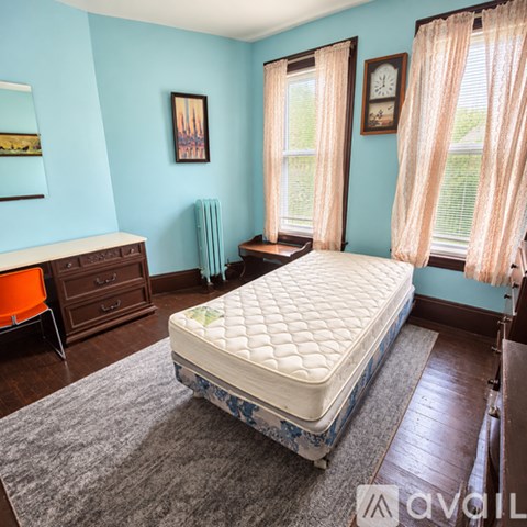 A bedroom with a bed, dresser, and window.