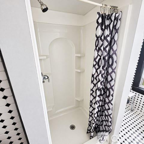 A shower with a black and white curtain.