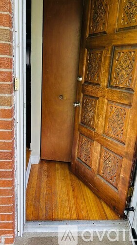 A wooden door with a carved design is open.