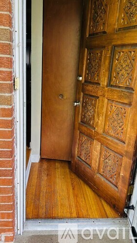 A wooden door with a carved design is open.