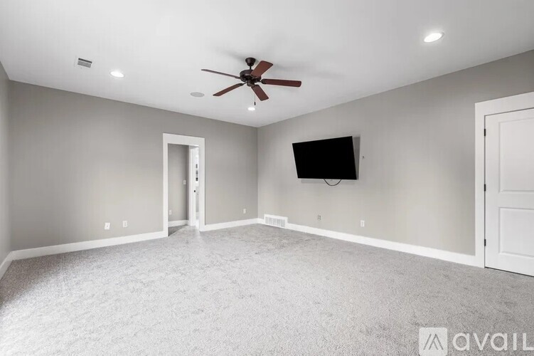 A spacious room with a ceiling fan and a flat screen TV mounted on the wall.