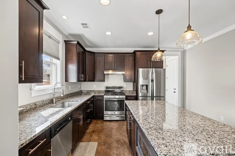 A kitchen with dark brown cabinets and granite countertops.