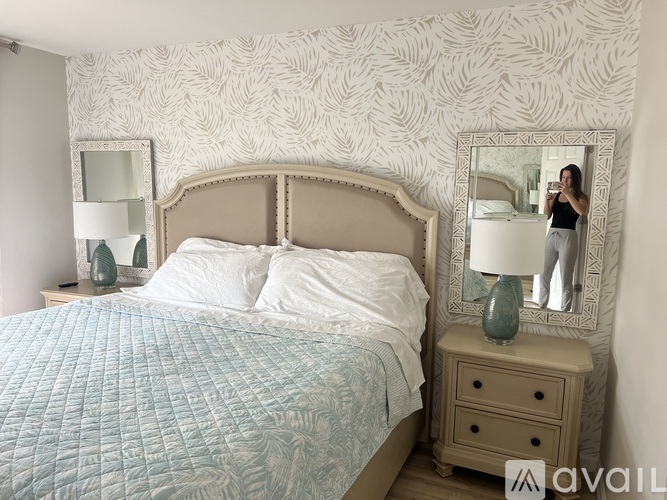 A woman is taking a selfie in a mirror in a bedroom.