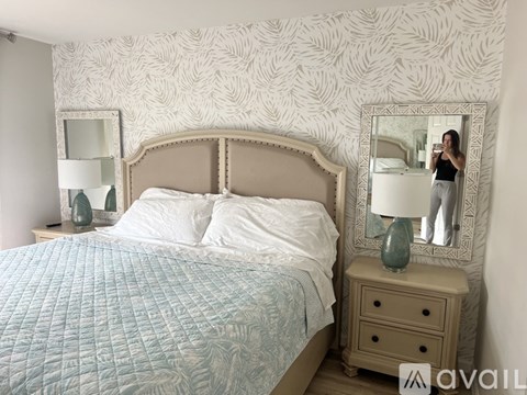 A woman is taking a selfie in a mirror in a bedroom.