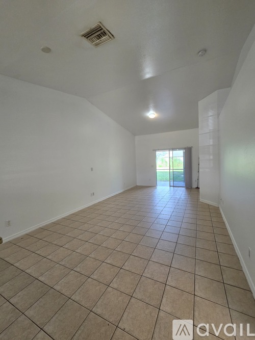 A room with tiled flooring and a window showing greenery outside.