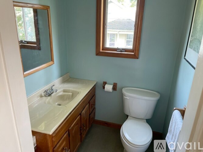 A bathroom with a toilet, sink, and mirror.