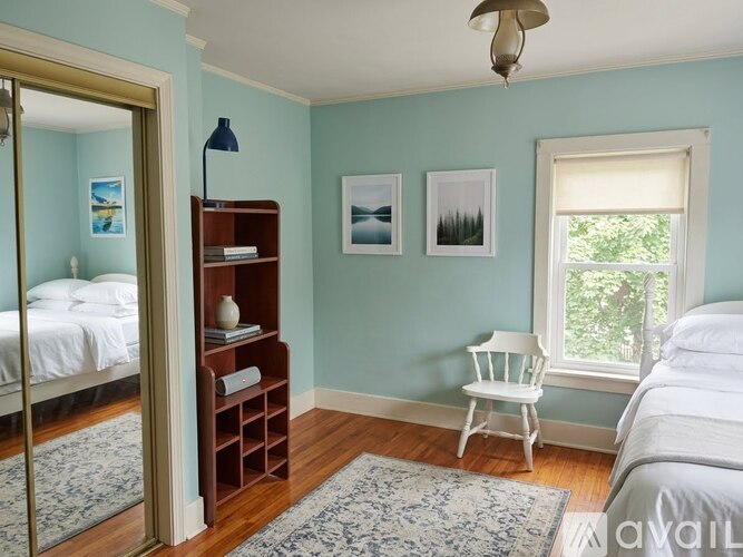 A bedroom with a white bed and a wooden bookshelf.