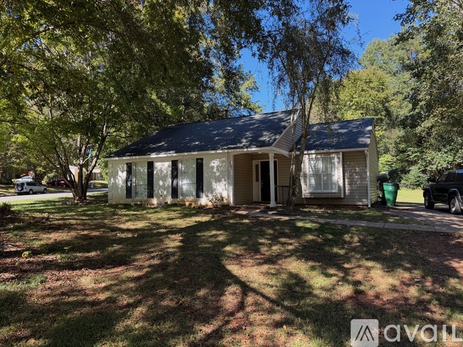 A house with a grey roof and white walls is for sale.