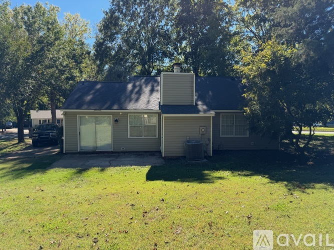 A house with a grey roof and a white garage door is surrounded by trees.