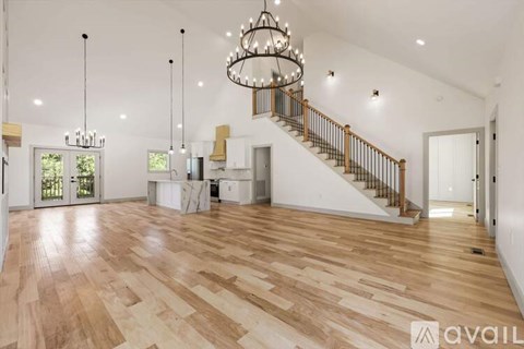 A spacious room with wooden flooring and a staircase with a metal railing.