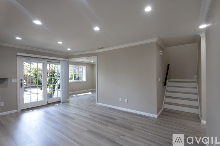 A spacious room with wooden flooring and a staircase leading to another level.