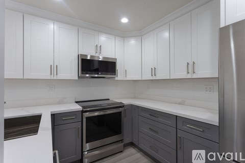 A kitchen with white cabinets and a stainless steel refrigerator.