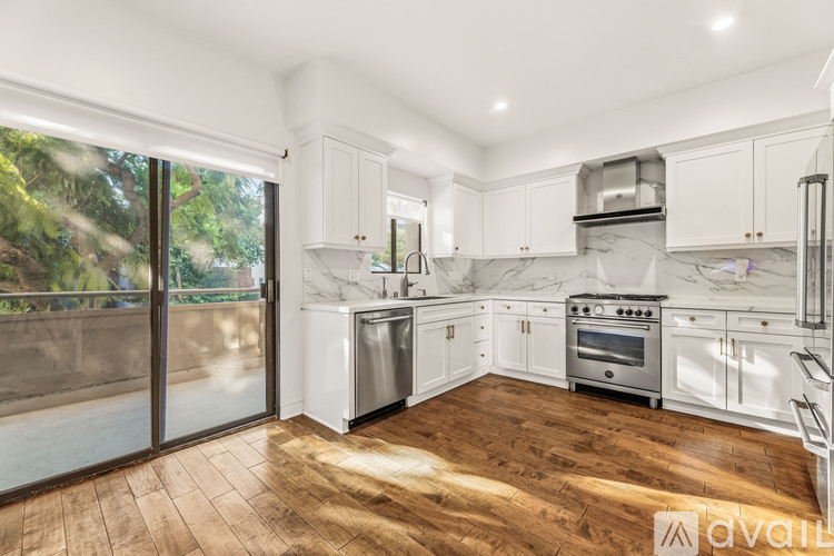 A kitchen with white cabinets and a wooden floor.