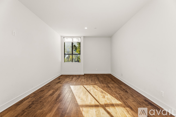 A room with wooden flooring and a window with a view of trees.