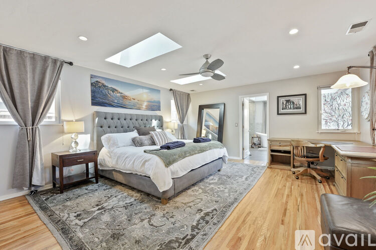 A bedroom with a large bed and a painting on the wall.