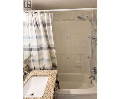 A bathroom with a shower curtain, sink, and bathtub.