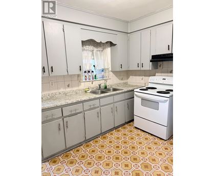 A kitchen with white cabinets and a patterned floor.
