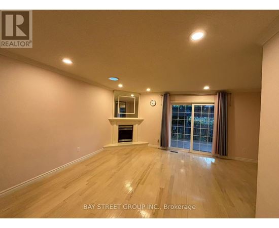 A spacious room with a fireplace and a window with curtains.