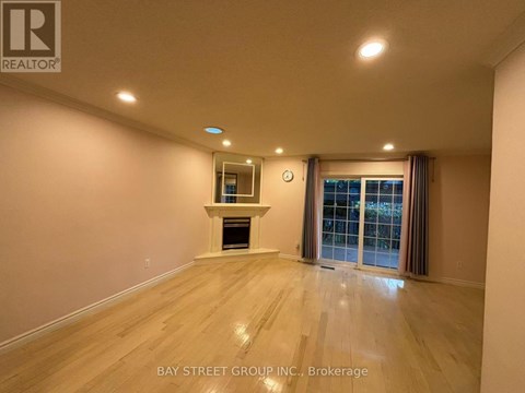 A spacious room with a fireplace and a window with curtains.