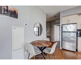 A modern kitchen with a wooden table and white chairs.