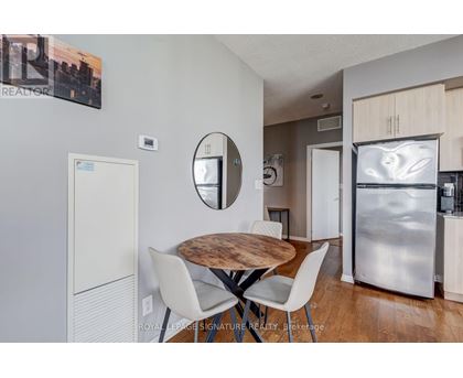A modern kitchen with a wooden table and white chairs.
