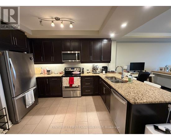 A kitchen with dark brown cabinets and a granite countertop.