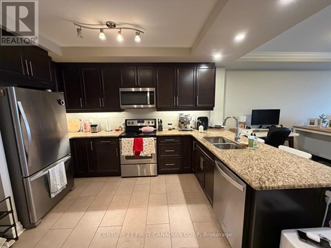 A kitchen with dark brown cabinets and a granite countertop.