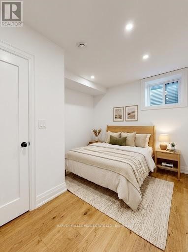 A bedroom with a bed, nightstand, and a window.