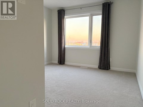 A room with a carpeted floor and a window with curtains.