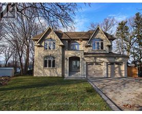 A large house with a stone facade and a garage is for sale.