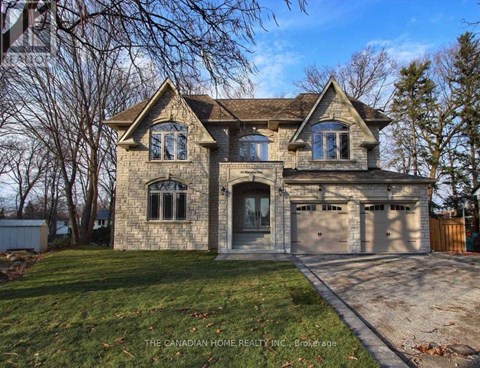 A large house with a stone facade and a garage is for sale.