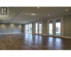 A spacious room with wooden floors and large windows.