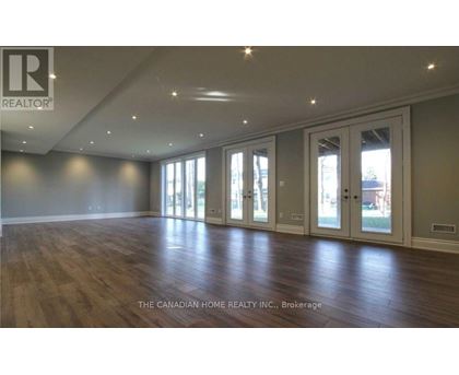 A spacious room with wooden floors and large windows.