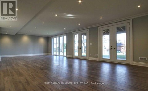 A spacious room with wooden floors and large windows.